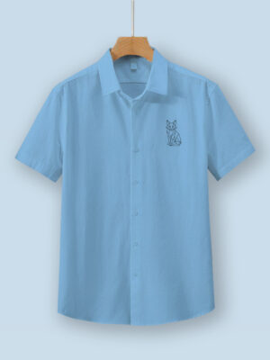 Light blue oversized cotton shirt with detailed vulpine (fox) embroidery on the chest, displayed on a wooden hanger.