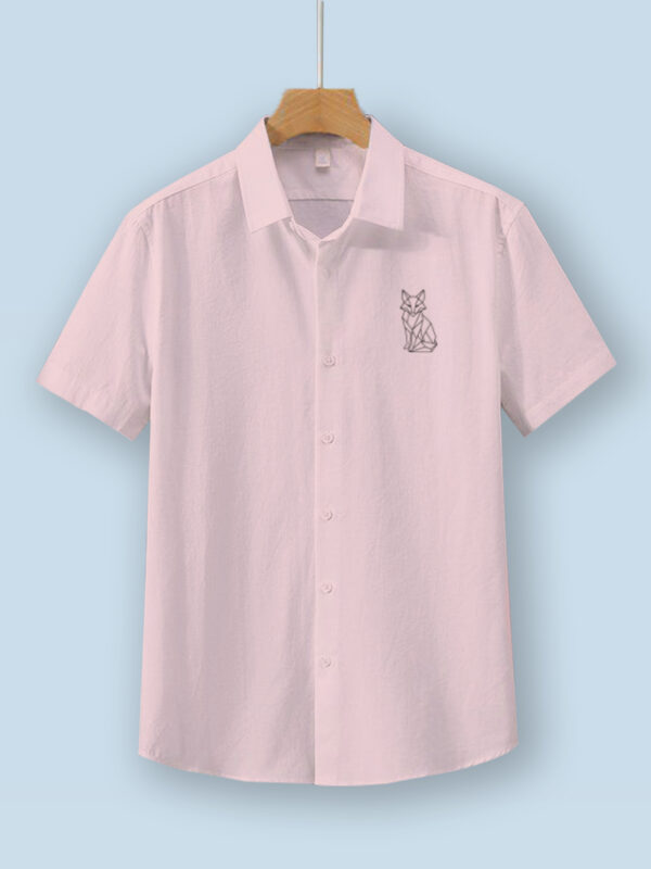 Light baby pink oversized cotton shirt with geometric fox embroidery on the chest, displayed on a wooden hanger.