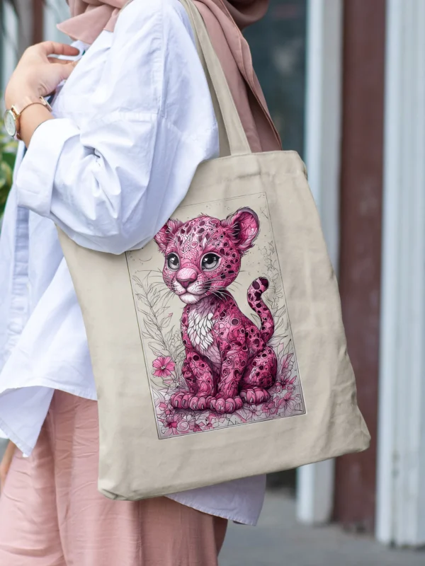 Woman carrying a natural cotton tote bag with a pink leopard cub illustration, part of LIVNT's WildBloom collection