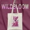 Canvas tote bag with pink leopard cub print and LIVNT logo, hanging against purple fabric background