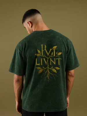 Model wearing a green acid-wash oversized T-shirt with LIVNT botanical logo on the back, unisex streetwear style.