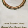 Kerala traditional jewelry set with gold mango leaf design and beautiful green emerald stones displayed on cream fabric
