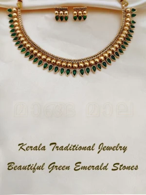 Kerala traditional jewelry set with gold mango leaf design and beautiful green emerald stones displayed on cream fabric