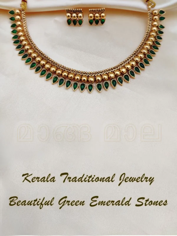 Kerala traditional jewelry set with gold mango leaf design and beautiful green emerald stones displayed on cream fabric
