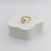 Angled side view of the elegant Moonlit Ring, showing the texture of the gold band and the shimmer of the central white pearl stone on a white display block.