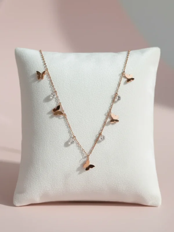 Delicate rose gold butterfly necklace with crystal accents, photographed on a soft cream cushion. The Ethereal Flutter Necklace by LIVNT symbolizes freedom, grace, and transformation — crafted with minimalist luxury design.