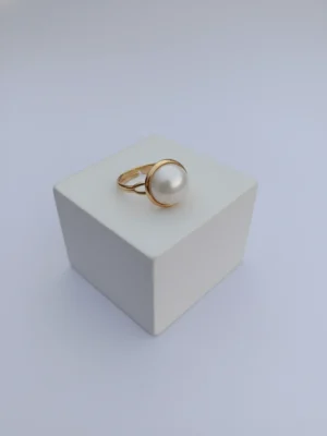 An angled, three-quarter view of the Orb Ring, showcasing the pearl's beautiful luster and the delicate structure of the gold setting on a white background.