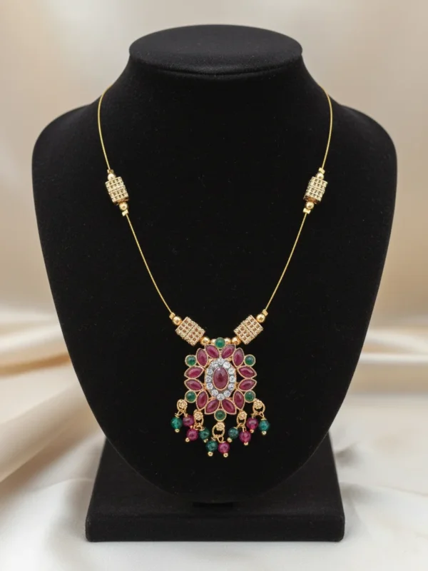 Petal Drop Invisible Necklace by LIVNT displayed on black velvet bust — elegant gold wire necklace with ruby, emerald, and crystal floral pendant for a luxurious statement look.