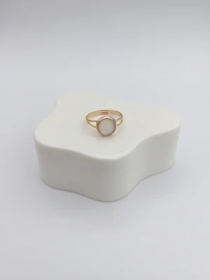 A lifestyle shot of the Moonlit Ring from the side, showing its delicate profile and adjustable gold-tone band on a clean white surface.