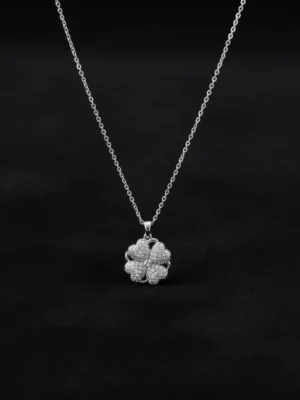 Spinning Heart Clover necklace on matte black background, low-key lighting, luxury jewelry display.