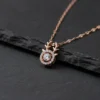 Close-up of the LIVNT rose gold fawn necklace pendant with its moving center stone, displayed on a textured dark slate surface for a modern contrast.