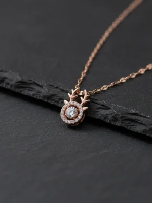 Close-up of the LIVNT rose gold fawn necklace pendant with its moving center stone, displayed on a textured dark slate surface for a modern contrast.
