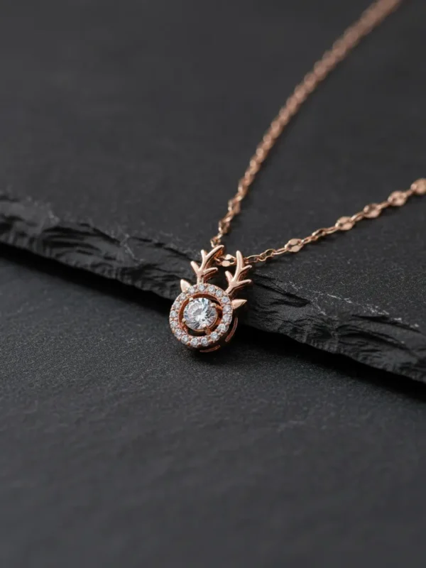 Close-up of the LIVNT rose gold fawn necklace pendant with its moving center stone, displayed on a textured dark slate surface for a modern contrast.