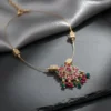 Luxury handcrafted Petal Drop Invisible Necklace with ruby, emerald, and gold-plated floral pendant resting on a soft grey silk background — symbolic jewelry by LIVNT representing grace and renewal.