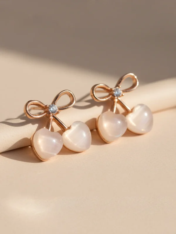 An angled, professional shot of the rose gold Cupid's Bow Earrings, showing their slight dimension and the pearlescent sheen of the heart stones.