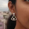Closeup of a woman wearing a LIVNT Pearl Triangle Stud earring, showcasing its elegant design against an urban background.