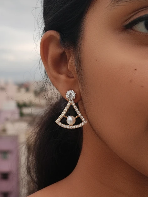 Closeup of a woman wearing a LIVNT Pearl Triangle Stud earring, showcasing its elegant design against an urban background.