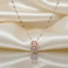 A delicate rose gold fawn necklace with a dancing diamond center stone, resting on a lustrous cream silk background reflecting its shine.