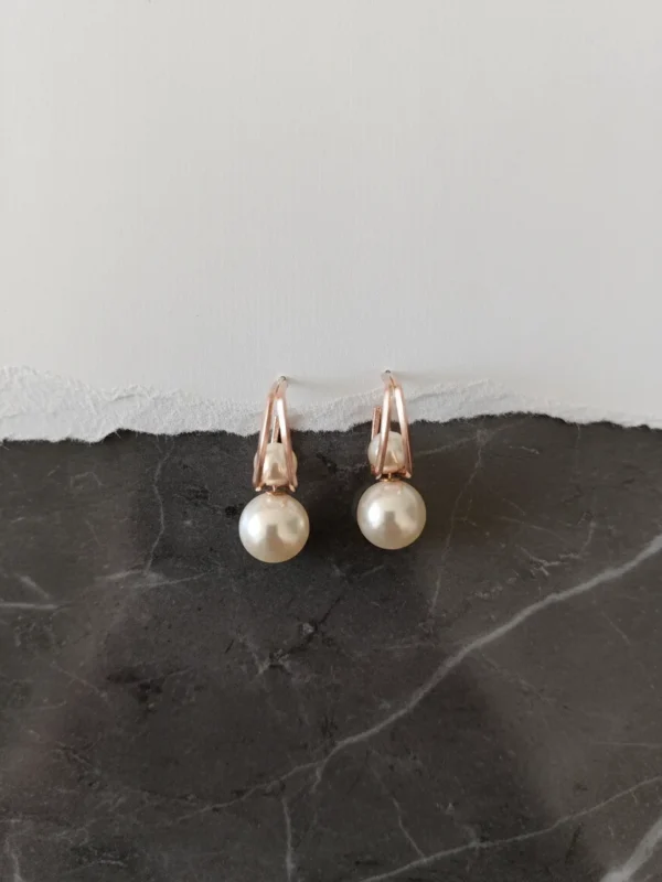 Lumina Modern Pearl Stud earrings at a semi-side angle on a torn white paper and dark marble surface, emphasizing depth.