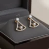 A pair of LIVNT Pearl Triangle Stud earrings displayed in an open luxury jewelry box, showcasing their exquisite detail and premium presentation.