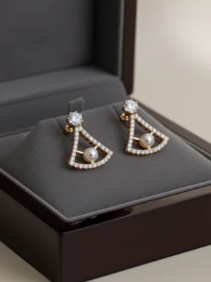 A pair of LIVNT Pearl Triangle Stud earrings displayed in an open luxury jewelry box, showcasing their exquisite detail and premium presentation.