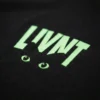 Close-up of LIVNT glow-in-the-dark cat eye logo on black t-shirt