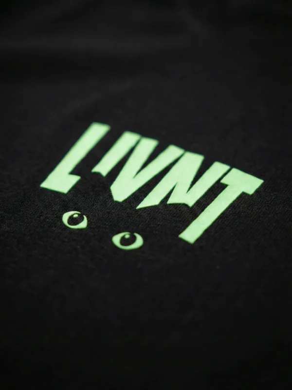 Close-up of LIVNT glow-in-the-dark cat eye logo on black t-shirt